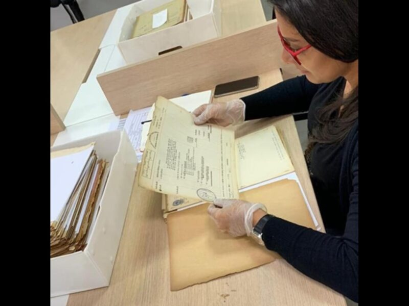 documento na horizontal sobre mesa onde há caixa com outros documentos