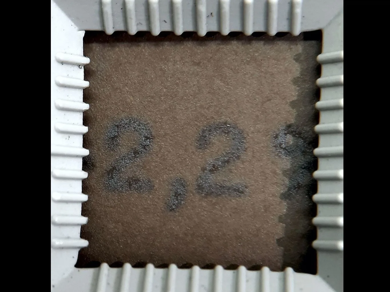 Detalhe de papel creme escurecido com o numeral “2,2%” datilografado em preto, dentro de esquadro branco quadrado