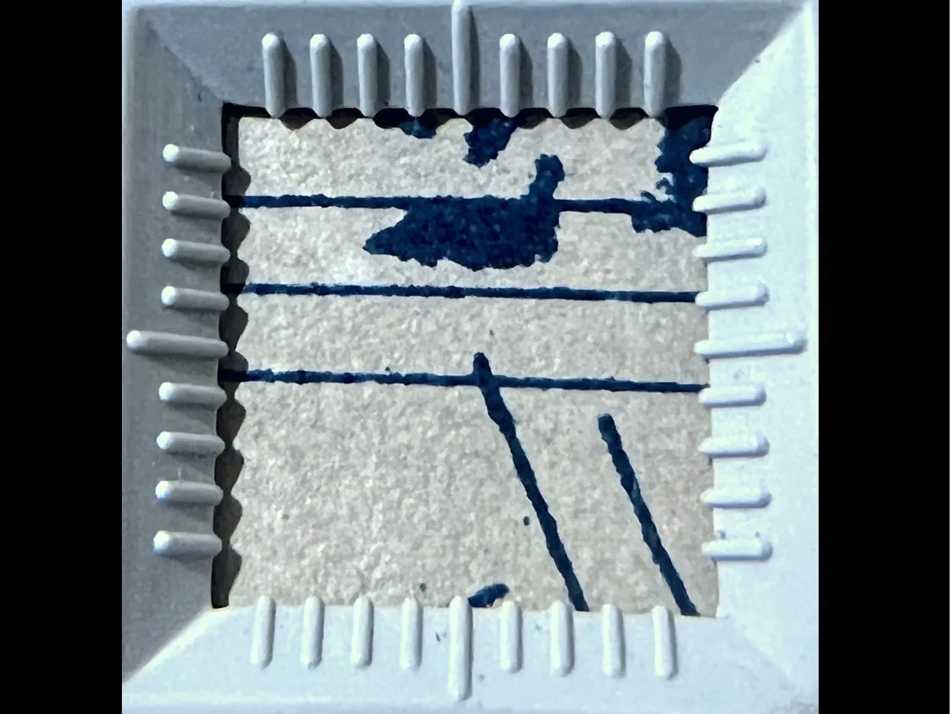 Detalhe de papel claro e traços e borrões azul escuros, dentro de um esquadro branco quadrado