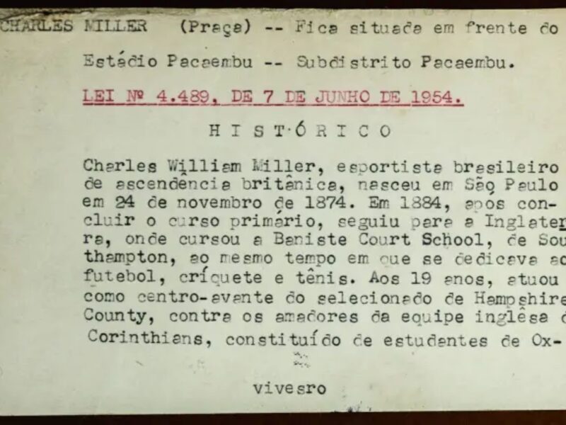 Ficha branca, levemente amarelada, datilografada com tinta preta e detalhes em vermelho sobre o histórico da Praça Charles Miller